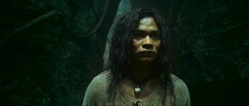 Movie still from “Ong Bak 2” (2008), directed by Tony Jaa – A man with long black hair wearing a necklace; Close Up shot, Low angle