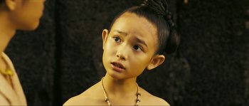 Movie still from “Ong Bak 2” (2008), directed by Tony Jaa – A young girl with a necklace looking at the camera; Close Up shot, High angle