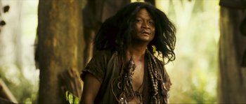 Movie still from “Ong Bak 2” (2008), directed by Tony Jaa – A man with dreadlocks is standing in the woods; Close Up shot, Low angle