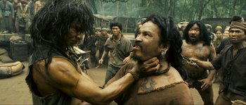 Movie still from “Ong Bak 2” (2008), directed by Tony Jaa – A group of people in the woods with a man touching another man's face; Close Up shot, Over the shoulder angle