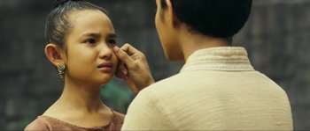 Movie still from “Ong Bak 2” (2008), directed by Tony Jaa – A woman looking in the mirror while another woman holds her hand to her ear; Close Up shot, Over the shoulder angle