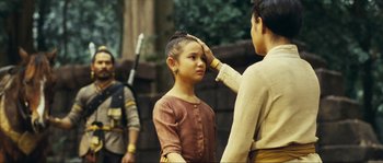 Movie still from “Ong Bak 2” (2008), directed by Tony Jaa – A young girl is being touched by an older man; Medium shot, Over the shoulder angle