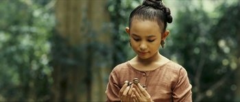Movie still from “Ong Bak 2” (2008), directed by Tony Jaa – A young girl holding a snail in her hands; Close Up shot, Over the shoulder angle