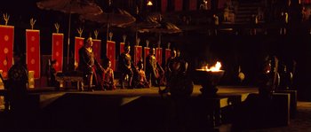 Movie still from “Ong Bak 2” (2008), directed by Tony Jaa – A group of people sitting in front of a fire pit; Extreme Wide shot, High angle