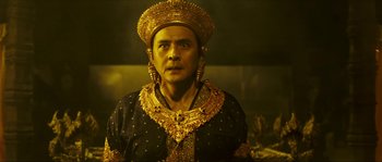 Movie still from “Ong Bak 2” (2008), directed by Tony Jaa – A man wearing a gold headdress and a black robe; Medium shot, Low angle