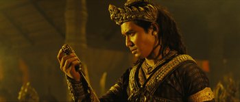 Movie still from “Ong Bak 2” (2008), directed by Tony Jaa – A man with a crown holding something in his hand; Close Up shot, Low angle