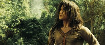Movie still from “Ong Bak 2” (2008), directed by Tony Jaa – A woman with long black hair standing in front of a forest; Medium shot, Low angle