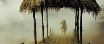 Movie still from “Ong Bak 2” (2008), directed by Tony Jaa – A man is running on a dock in the fog; Wide shot, High angle