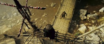 Movie still from “Ong Bak 2” (2008), directed by Tony Jaa – A man walking across a bridge with a monkey on it's back; Wide shot, Overhead angle
