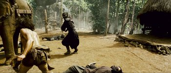 Movie still from “Ong Bak 2” (2008), directed by Tony Jaa – A man in a black suit is playing a game of baseball; Wide shot, High angle