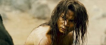 Movie still from “Ong Bak 2” (2008), directed by Tony Jaa – A man with long brown hair is looking at the camera; Close Up shot, Low angle
