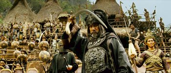 Movie still from “Ong Bak 2” (2008), directed by Tony Jaa – A man dressed as a barbarian holding a weapon; Medium shot, Low angle