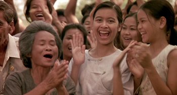 Movie still from “Ong-Bak: The Thai Warrior” (2003), directed by Prachya Pinkaew – A group of people clapping and smiling for the camera; Medium shot, Low angle