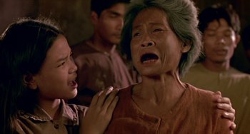 Movie still from “Ong-Bak: The Thai Warrior” (2003), directed by Prachya Pinkaew – An older woman is crying as a young boy looks on; Close Up shot, Over the shoulder angle