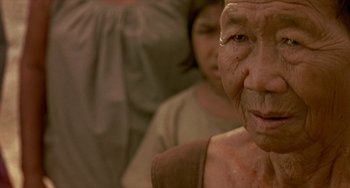 Movie still from “Ong-Bak: The Thai Warrior” (2003), directed by Prachya Pinkaew – An old woman is looking into the camera; Close Up shot, Low angle