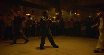 Movie still from “Ong-Bak: The Thai Warrior” (2003), directed by Prachya Pinkaew – A man is singing in front of a crowd; Wide shot, High angle