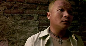 Movie still from “Ong-Bak: The Thai Warrior” (2003), directed by Prachya Pinkaew – A man wearing a white shirt and a white jacket; Close Up shot, Low angle