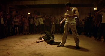 Movie still from “Ong-Bak: The Thai Warrior” (2003), directed by Prachya Pinkaew – Two men are on the ground in front of a crowd; Wide shot, High angle