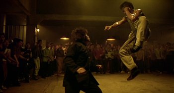 Movie still from “Ong-Bak: The Thai Warrior” (2003), directed by Prachya Pinkaew – Two people are dancing in a crowd of people; Wide shot, Low angle