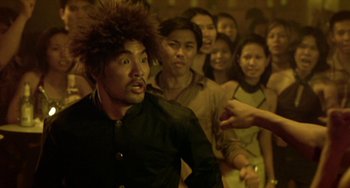 Movie still from “Ong-Bak: The Thai Warrior” (2003), directed by Prachya Pinkaew – A group of people standing in a room; Medium shot, Over the shoulder angle