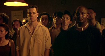 Movie still from “Ong-Bak: The Thai Warrior” (2003), directed by Prachya Pinkaew – A group of people standing in a dark room; Medium shot, Low angle