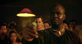 Movie still from “Ong-Bak: The Thai Warrior” (2003), directed by Prachya Pinkaew – A man is holding a glass in his hand; Close Up shot, Low angle