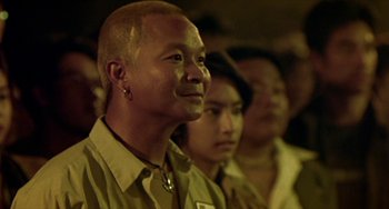 Movie still from “Ong-Bak: The Thai Warrior” (2003), directed by Prachya Pinkaew – A group of people standing next to each other in a room; Close Up shot, Over the shoulder angle