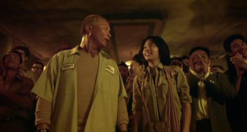 Movie still from “Ong-Bak: The Thai Warrior” (2003), directed by Prachya Pinkaew – A man and a woman standing next to each other; Medium shot, Low angle