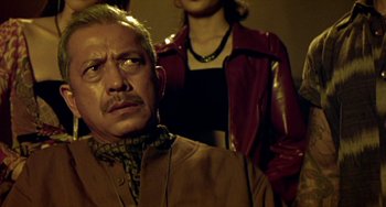 Movie still from “Ong-Bak: The Thai Warrior” (2003), directed by Prachya Pinkaew – An older man and a young woman standing next to each other; Close Up shot, Low angle