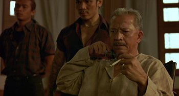 Movie still from “Ong-Bak: The Thai Warrior” (2003), directed by Prachya Pinkaew – An older man is looking at a pair of scissors; Close Up shot, Over the shoulder angle