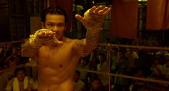 Movie still from “Ong-Bak: The Thai Warrior” (2003), directed by Prachya Pinkaew – A man in a boxing ring with his hands wrapped in bandages; Medium shot, Low angle