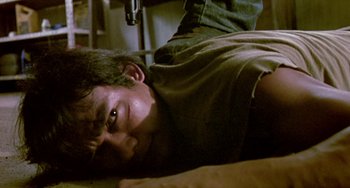 Movie still from “Ong-Bak: The Thai Warrior” (2003), directed by Prachya Pinkaew – A man laying on the ground in a room; Close Up shot, Low angle