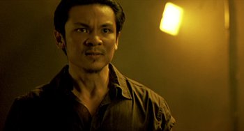 Movie still from “Ong-Bak: The Thai Warrior” (2003), directed by Prachya Pinkaew – A person wearing a brown shirt; Close Up shot, Low angle