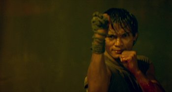 Movie still from “Ong-Bak: The Thai Warrior” (2003), directed by Prachya Pinkaew – A man with a fist up in the air; Close Up shot, Low angle