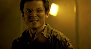 Movie still from “Ong-Bak: The Thai Warrior” (2003), directed by Prachya Pinkaew – A person wearing a brown shirt; Close Up shot, Low angle