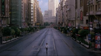 Movie still from “Open Your Eyes” (1997), directed by Alejandro Amenábar – A man walking across a street in a city; Extreme Wide shot, High angle