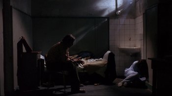 Movie still from “Open Your Eyes” (1997), directed by Alejandro Amenábar – A man sitting on a chair in a dark room; Wide shot, High angle