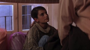 Movie still from “Open Your Eyes” (1997), directed by Alejandro Amenábar – A woman sitting on a couch in a room; Medium shot, Over the shoulder angle