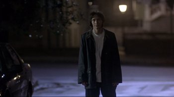 Movie still from “Open Your Eyes” (1997), directed by Alejandro Amenábar – A young man standing in the dark in front of a building; Medium shot, Over the shoulder angle