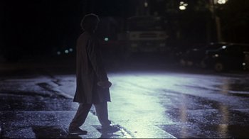 Movie still from “Open Your Eyes” (1997), directed by Alejandro Amenábar – A man walking down a street at night; Wide shot, Over the shoulder angle