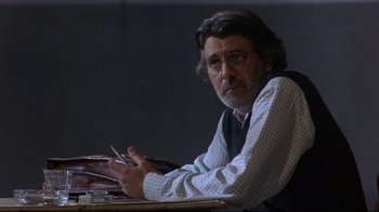 Movie still from “Open Your Eyes” (1997), directed by Alejandro Amenábar – A man sitting at a table holding a pen; Medium shot, Over the shoulder angle