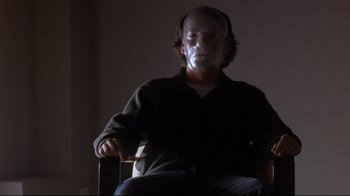 Movie still from “Open Your Eyes” (1997), directed by Alejandro Amenábar – A man sitting in a chair with a mask on his face; Medium shot, Low angle