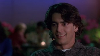 Movie still from “Open Your Eyes” (1997), directed by Alejandro Amenábar – A man with long brown hair smiles for the camera; Close Up shot, Over the shoulder angle