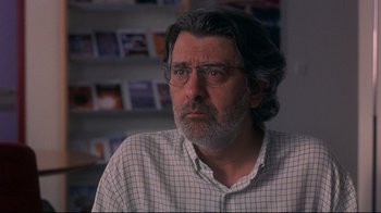 Movie still from “Open Your Eyes” (1997), directed by Alejandro Amenábar – A man with a beard and glasses looking at the camera; Close Up shot, Over the shoulder angle