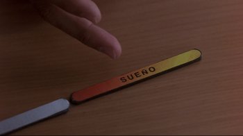 Movie still from “Open Your Eyes” (1997), directed by Alejandro Amenábar – A hand is touching the word suero on a wooden table; Extreme Close Up shot, High angle