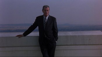 Movie still from “Open Your Eyes” (1997), directed by Alejandro Amenábar – A man in a suit and tie standing next to a railing; Medium shot, Low angle