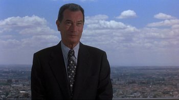 Movie still from “Open Your Eyes” (1997), directed by Alejandro Amenábar – A man in a suit and tie standing in front of a city skyline; Medium shot, Low angle