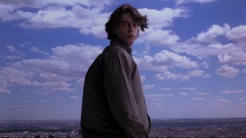 Movie still from “Open Your Eyes” (1997), directed by Alejandro Amenábar – A man standing on top of a hill in front of a city; Medium shot, Low angle