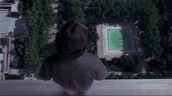 Movie still from “Open Your Eyes” (1997), directed by Alejandro Amenábar – A person sitting on a ledge looking out over a pool; Extreme Wide shot, Overhead angle