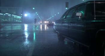 Movie still from “Opening Night” (1977), directed by John Cassavetes – A car driving down a wet street in the rain; Extreme Wide shot, Low angle